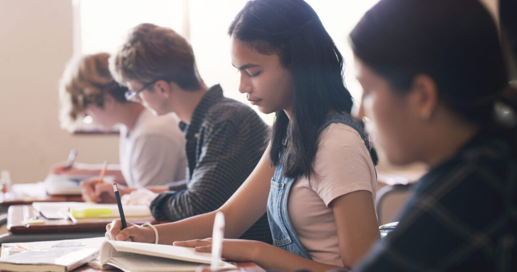 Shot of teenagers writing an exam in a classroom