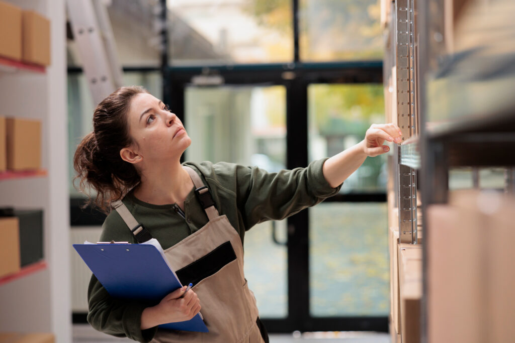 Lagerarbetare letar bland hyllor med kartonger och boxar i olika storlekar